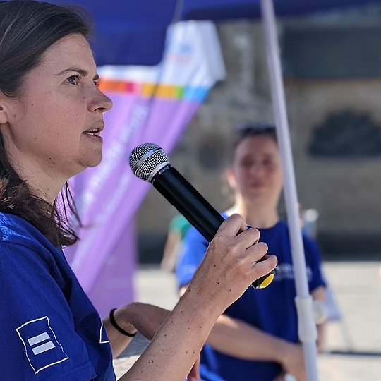 Eine Mitarbeiterin der Selbsthilfe-Kontaktstelle Bonn begrüßt die Teilnehmer des Selbsthilfetages per Mikrofon.