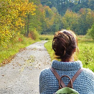 Eine Frau mit Rucksack spaziert durch die Natur
