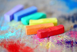 Bunte Kreidestifte liegen auf einer Pappunterlage