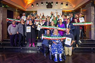 Auf einer Bühne sind die GewinnerInnen des Selbsthilfepreis NRW 2024 zu sehen. 