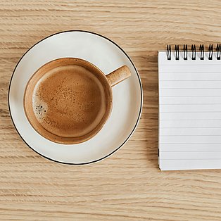 Ein Block liegt neben einer Tasse Kaffee