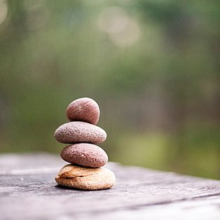 Foto von mehreren Steinen, die aufeinander liegen. Symbol für "Balance".