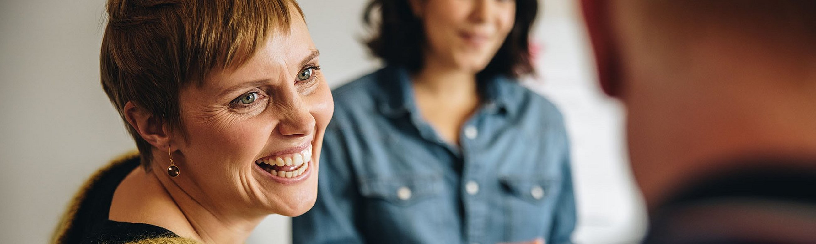 Drei Personen unterhalten sich angeregt, eine Frau lacht einen Mann dabei sehr freundlich an